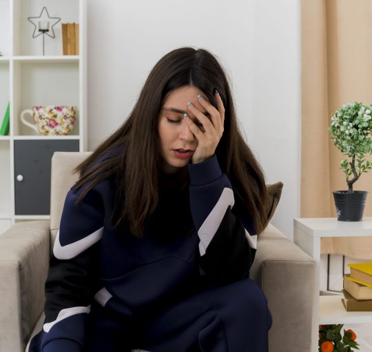 tired-young-pretty-caucasian-woman-sitting-armchair-designed-living-room-putting-hand-face-with-closed-eyes
